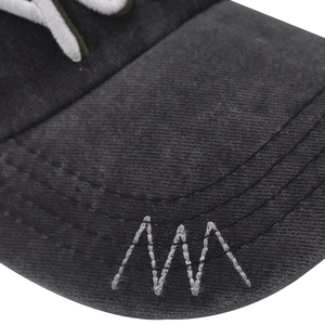 Detailed close-up of white decorative stitching on a dark grey cotton baseball cap brim