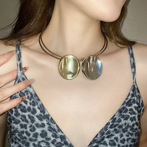 Detail showing two-tone gold and silver oval pendant necklace on a model's neck