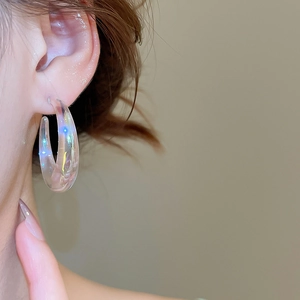 Close-up of a model wearing iridescent C-shaped acrylic earrings with a rainbow shine finish