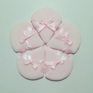 Five pink triangular powder puffs with ribbon bows arranged in a decorative floral pattern