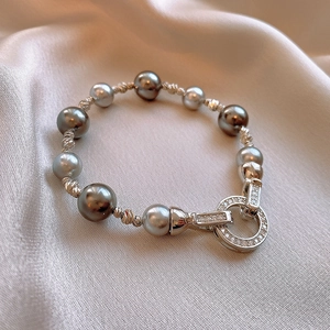 Dettaglio del bracciale con perle grigie, sfere d'argento e chiusura a cerchio in zirconi