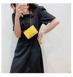 Detail of yellow quilted heart chain bag shown on a black dress for kids fashion