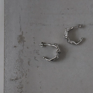 Detailed macro view of silver crumpled foil texture on stainless steel earrings
