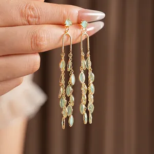 Boucles d'oreilles longues à pampilles en opale verte et finition dorée sur main élégante