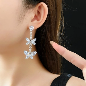 Gros plan de boucles d'oreilles papillon avec zircons portées par un mannequin