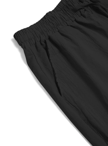 Detail of black linen trousers showing elastic waistband and side pocket texture