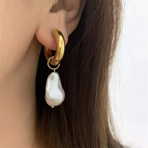 Close-up of elegant 18K gold stainless steel hoop earring with baroque pearl on model