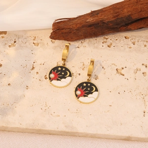Detail von Vintage-Goldohrringen mit Mond- und Sonnenmotiven auf schwarzer Emaille