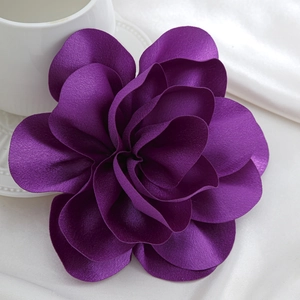 Detailed view of dark purple satin rose brooch on elegant white silk and ceramic background