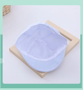 Breathable cotton inner lining of a light blue baby cap on a wooden frame