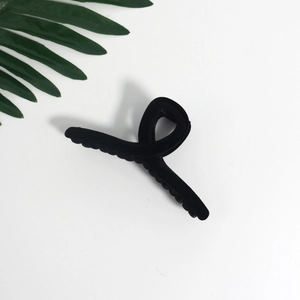 Minimalist black velvet claw clip with crossed matte finish design on white background