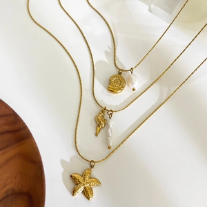 Golden ocean theme necklaces with conch starfish pendants and pearls in a 45-degree view
