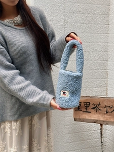Close-up detail of soft light blue plush bottle sleeve with fluffy faux fur texture
