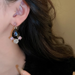 Macro shot of luxury drop earring with black gemstone and pink crystals on model