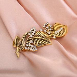 Vintage golden leaf hair clip with crystal rhinestones on elegant pink silk background