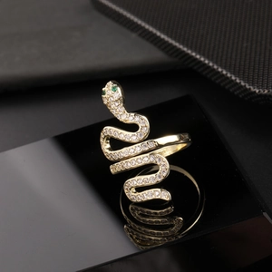 Macro shot of gold snake ring with white cubic zirconia and green gemstone eyes