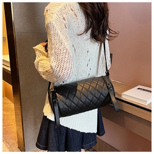 Gesteppte schwarze Zylindertasche getragen zum weißen Strickoutfit im Alltag