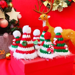Close-up of knit Christmas pet hats with pompoms on a festive gift box background