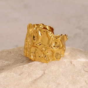 Macro shot of 18k gold irregular lava texture ring on natural stone base detail