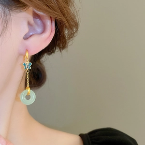 Détail des boucles d'oreilles papillon dorées avec pendentif en jade sur mannequin
