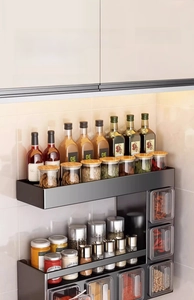Detailed view of wall-mounted black kitchen spice rack with integrated clear seasoning jars