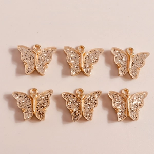 Macro shot of 6 gold alloy butterfly pendants with silver glitter for DIY jewelry making