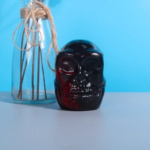 Macro shot of a dark translucent glass skull storage jar with detailed facial carving