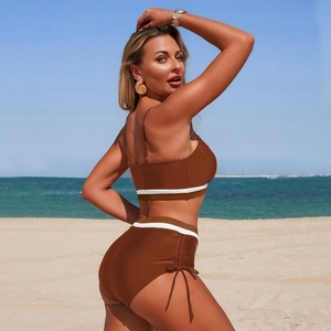 Detail of high-waisted bikini with side drawstrings and contrast white stripes in caramel