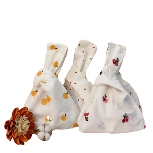 Japanese knot wrist bags with citrus, heart, and cherry prints on dotted jacquard fabric