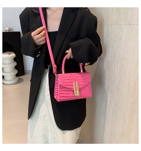 Macro detail of hot pink faux leather handbag with crocodile pattern and gold clasp lock