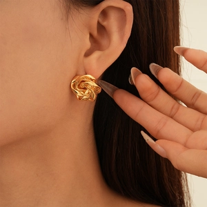 Elegant gold metal flower stud earrings with layered petals shown on model's ear