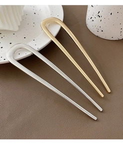 U-shaped metal hairpins in gold and silver finish displayed on a brown textured surface