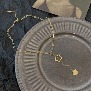 Minimalist gold star fringe pendant necklace with paperclip chain on ceramic tray