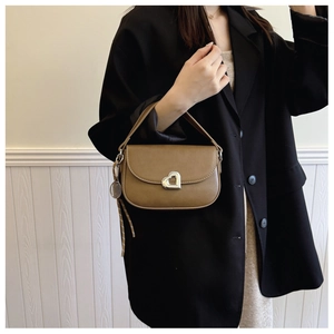 Detail of tan leather saddle bag with silver heart buckle and tennis racket charm
