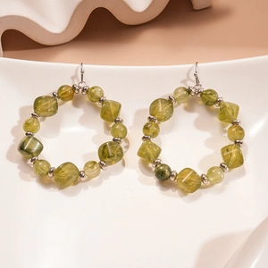 Detailed macro view of olive green resin beads and silver metal spacers on large hoop earrings