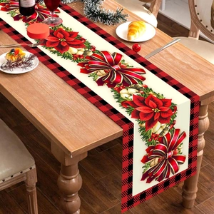 Christmas table runner with red poinsettia and golden bells on rustic wooden table