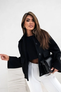 Détail de la texture en laine noire et boutons simples sur une veste élégante minimaliste