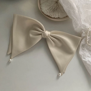 Detailed view of a French cream satin bow hair clip with elegant pearl pendant drops