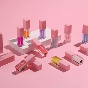 Glossy lip oil collection in 4.5ml transparent tubes with pink caps on geometric props