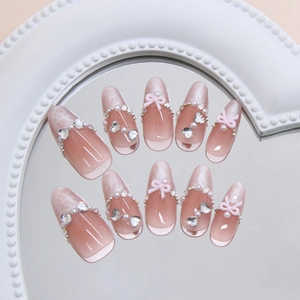 Pink cat-eye press-on nails with 3D bows, pearls and crystals in almond shape
