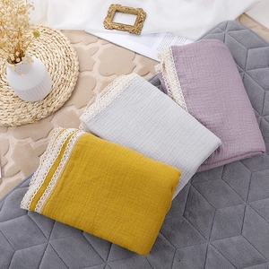 Detail of soft muslin baby blankets with lace edges in ginger, grey and lavender
