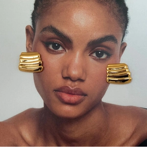 Close-up of 18K gold-plated stainless steel earrings with layered wave textures