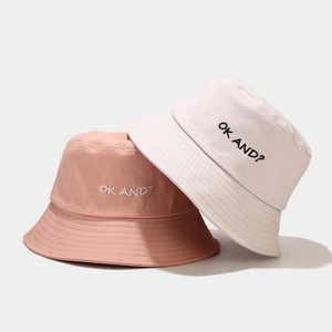 Detail of OK AND? embroidery on cotton canvas bucket hats in pink and beige colors