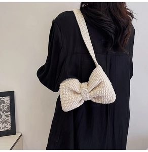 Détail d'un sac à bandoulière en tricot crème fait main avec un grand nœud sur un modèle