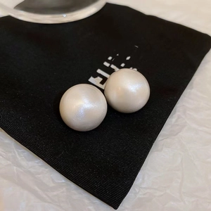 Minimalist white round pearl stud earrings with gold plating on black velvet pouch