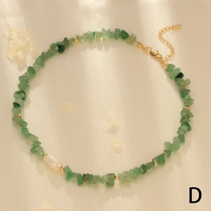 Macro detail of handmade green crushed stone necklace with baroque pearl on silk fabric