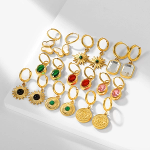 Gros plan sur les boucles d'oreilles en acier doré 18 carats avec pierres et breloques papillon