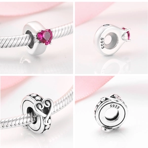 Macro detail of S925 sterling silver heart charms with pink gemstone and hollow patterns