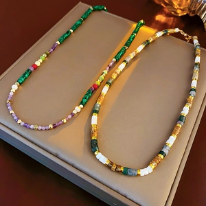 Detail of beaded necklaces with colorful gems and gold accents on a jewelry tray