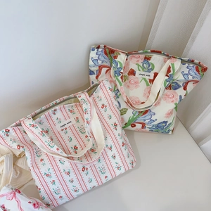 Détail de sacs fourre-tout en toile à fleurs et rayures avec des anses tissées beiges